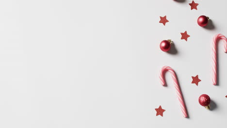 video of baubles, candy canes and stars christmas decorations with copy space on white background