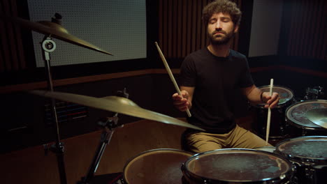 musician playing rock music in studio. drummer closing eyes in concert hall.