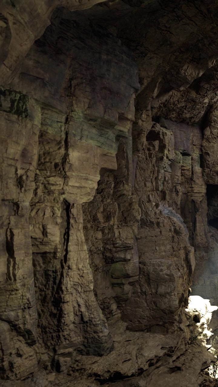 Esplorando pareti rocciose di una grotta vicino a una piccola fonte di luce durante il giorno.