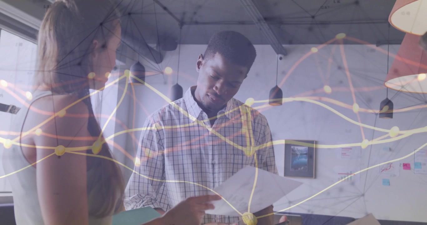 Woman opening binder showing document to man explaining tech chart animating network overlay