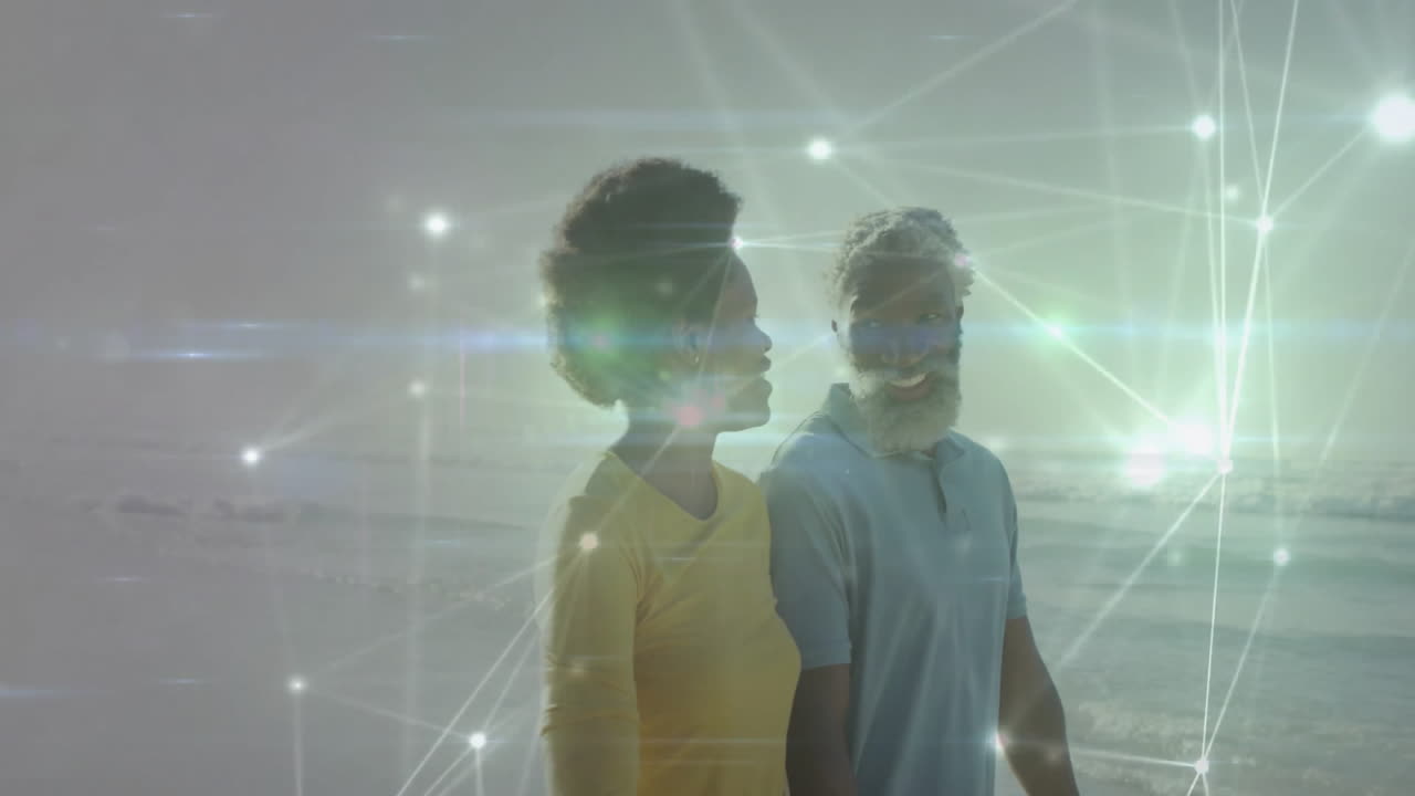 Man and woman walking along sandy shoreline, showing digital technology network with glowing nodes