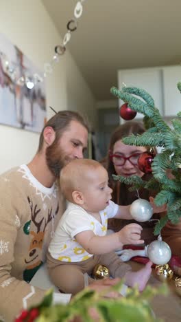 family decorating a christmas tree with baby