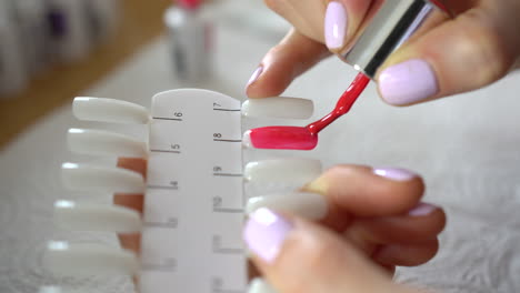 manos de mujer pintando plantilla de punta de uñas con laca híbrida, primer plano