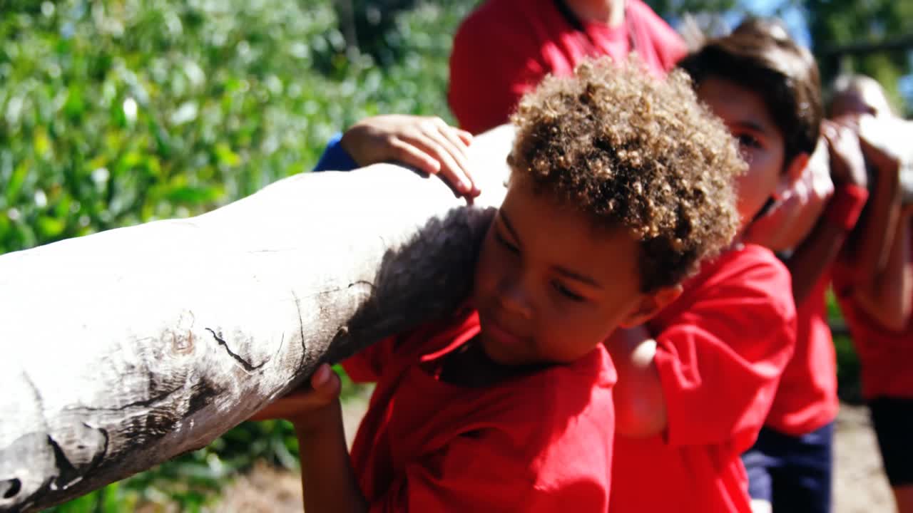niños cargando troncos de madera durante el entrenamiento