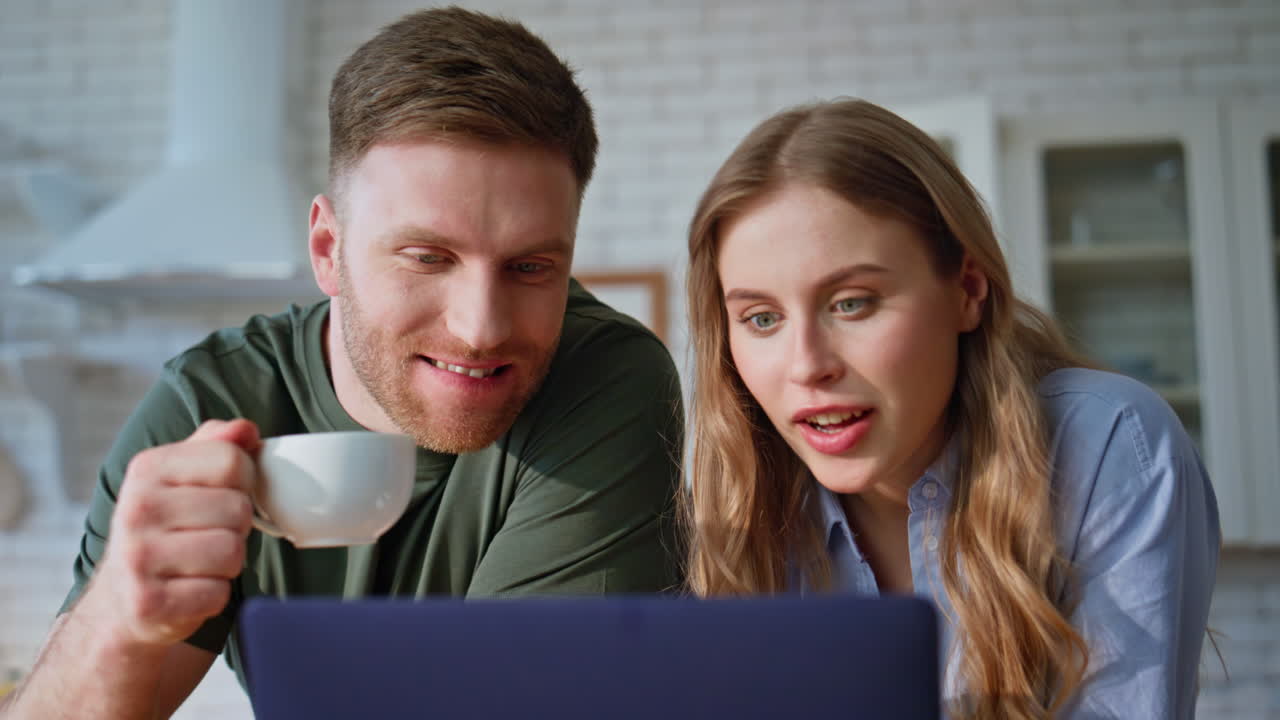 Laughing spouses watching laptop family morning closeup. Couple drinking coffee