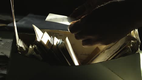 searching hands sorting old mail document letters in dimly lit room close-up
