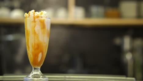 vista de batido recién hecho con goteo de caramelo al lado del vidrio