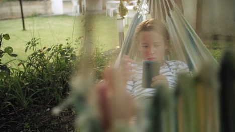 young boy relaxing in hammock with smartphone