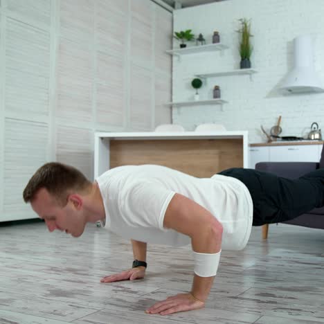 sportive guy doing push ups at home. young man exercising on a floor with his legs on a couch. workout in apartment during isolation