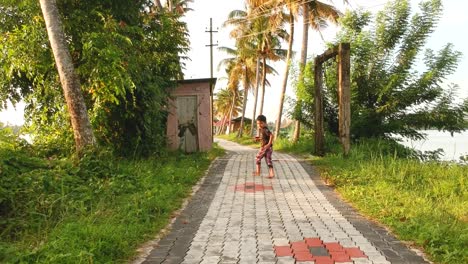 young boy running in front of camera looking backwards,garden path