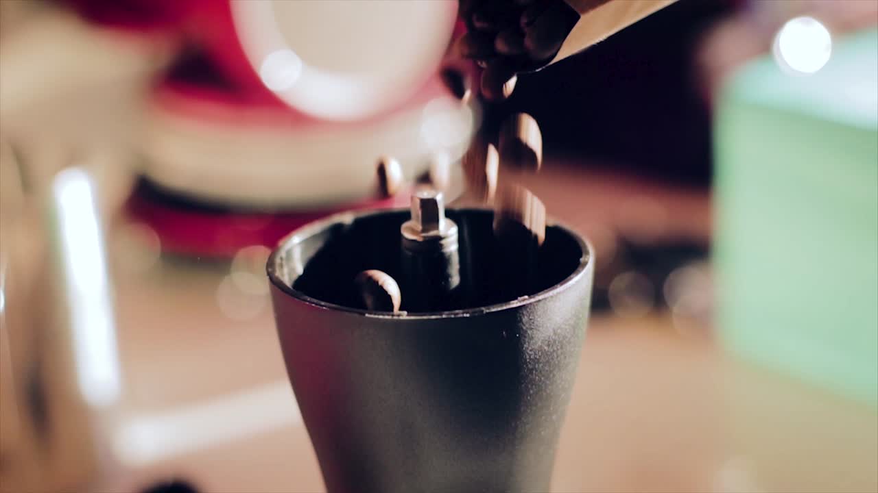 cámara lenta cayendo granos de café en molinillo de mano hario