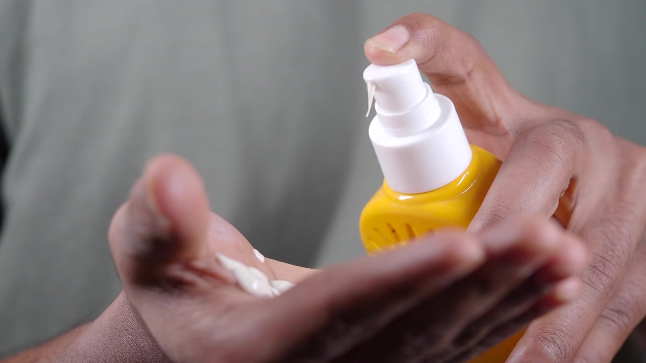 Person Applying Moisturizing Cream from Yellow Pump Bottle