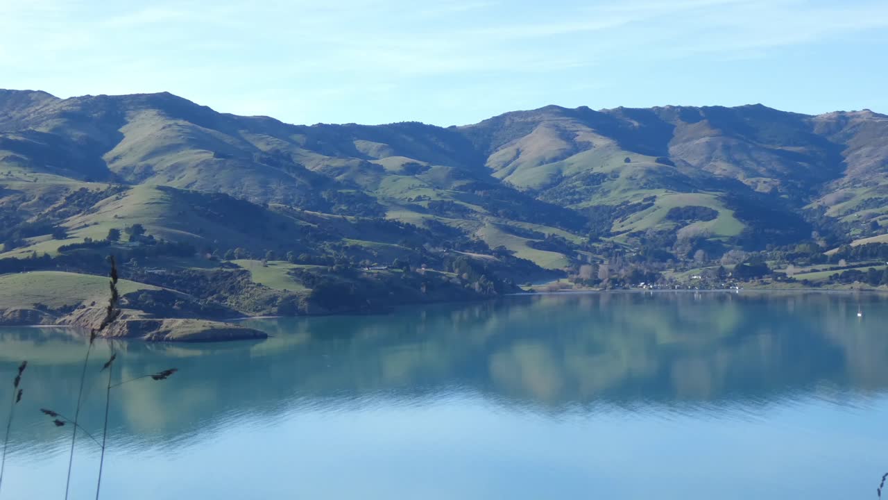 el sol de mediados de invierno temprano en la mañana proyecta largas sombras en los valles de las colinas de la península - bahía de takamatua, puerto de akaroa