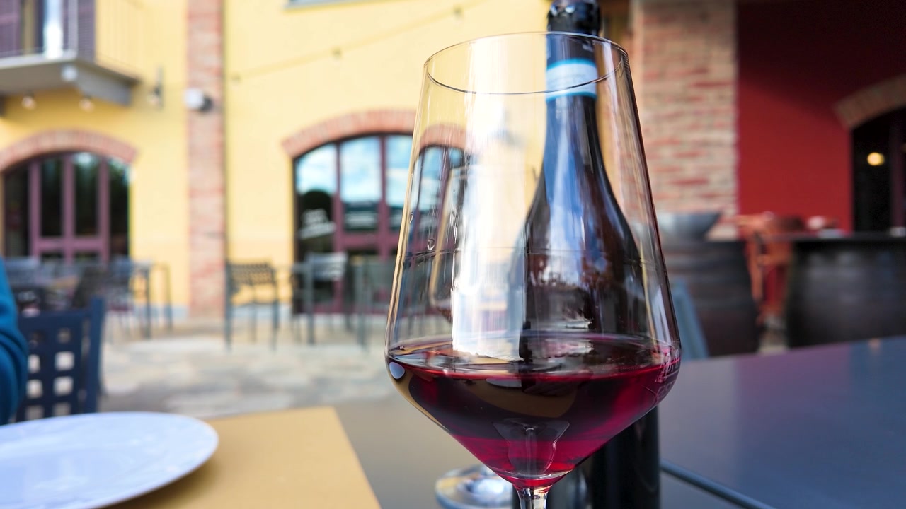 Primo piano di un bicchiere di vino rosso su un tavolo in una cantina italiana all'aperto