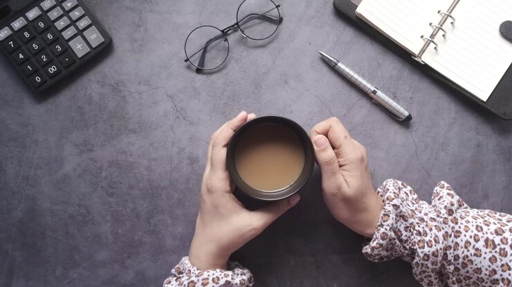Donna che si gode il caffè alla sua scrivania