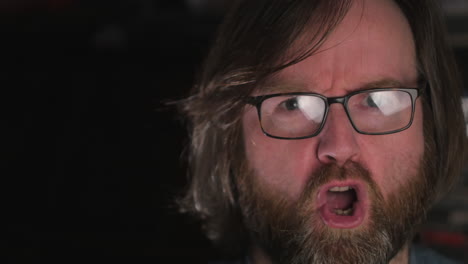 man with long hair and wearing eyeglasses, repeatedly saying no without voice to his audience, close up