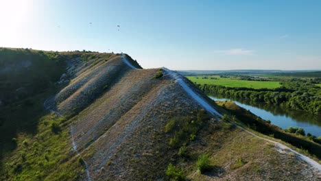 scenic aerial view of hills, river, and paragliders