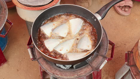 fish frying in a pan over an open fire