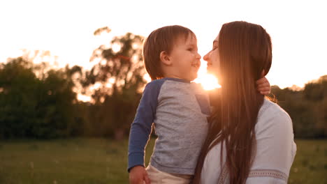 The-son-kisses-his-mother-sitting-at-sunset-in-a-field-hugging-and-loving-mother.-Mother's-day