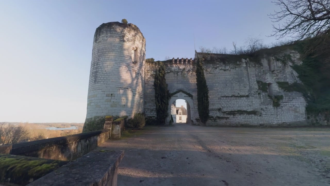 Antica cinta muraria del Castello di Saint-Aignan con arco, immersa in un paesaggio tranquillo all'alba.