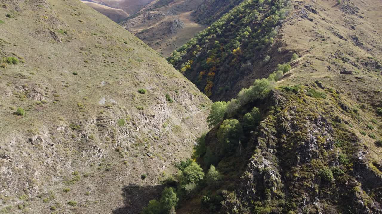 Approaching aerial movement to a narrow mountain pass surrounded by steep rocky slopes, Khevsureti, Mtskheta-Mtianeti, Georgia