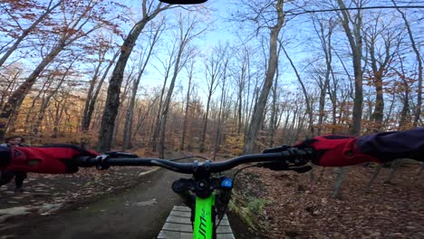 mtb rider pov jumping wooden obstacle in fall trail sun setting