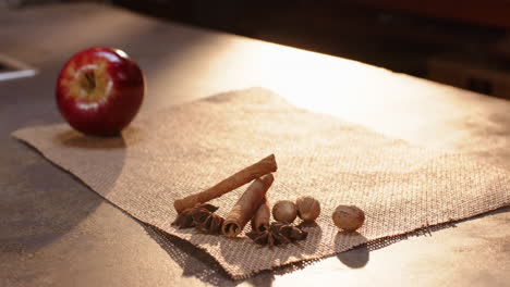 senior woman placing freshly baked apple pie on table with spices and apple, at home