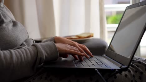 Woman-working-from-home-on-the-couch-in-pyjamas-hand-keyboard-close-up-shot