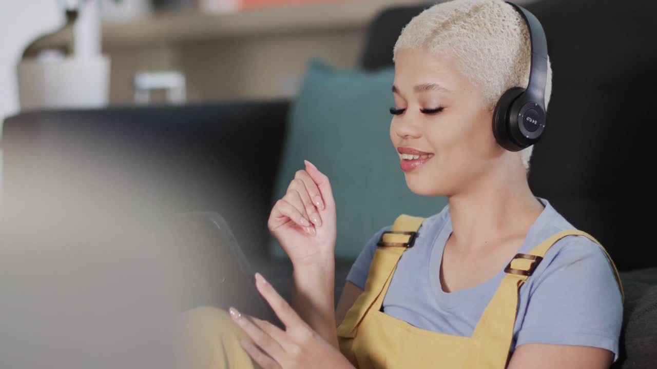 Happy biracial woman using smartphone and listening to music in slow motion