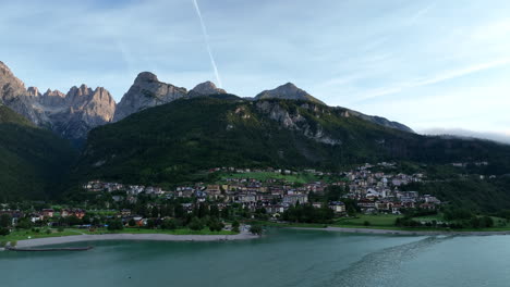 molveno estableciendo una vista aérea hacia la idílica comuna montañosa de los dolomitas al atardecer