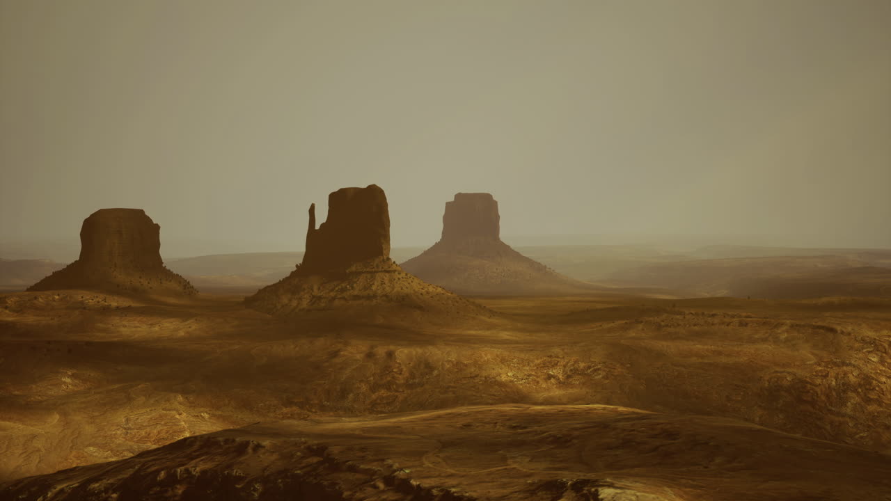 Golden hour over a desert with distant rock formations and haze