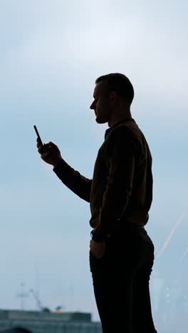 handsome businessman writing notes from smartphone at modern office vertical video