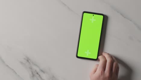 Overhead-Studio-Shot-Of-Man-Using-Green-Screen-Mobile-Phone-1