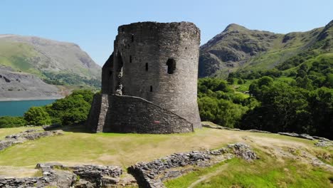 ripresa aerea delle rovine del castello in galles con la splendida campagna sullo sfondo tra cui un lago, dolci colline e alberi