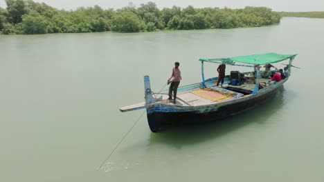 aerial shot capturing a fisherman pulling a net from a boat in the mangroves of the indus river delta.