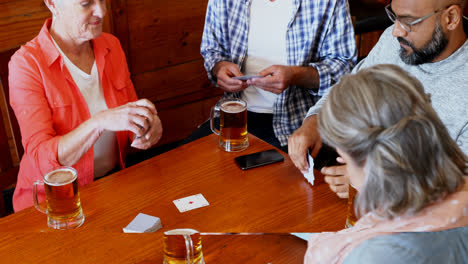 happy friends playing cards while having glass of beer 4k