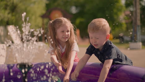 little boy and elder girl play with water in inflatable pool