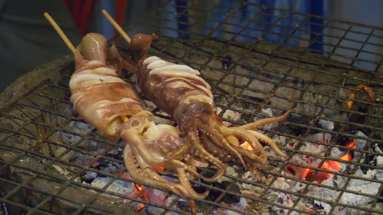 대나무 막대기에  ⁇ 인 오징어는 뜨거운 목탄에  ⁇ 여 있습니다. 태국 야시장 거리 음식 부스