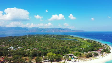 Green-tropical-island-on-a-blue-scenery-with-sea-around-white-beach-and-turquoise-lagoon-on-a-bright-sky-background-with-white-clouds-in-Indonesia