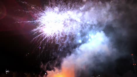 colorful fireworks display illuminating the night sky behind a dark, monolithic building