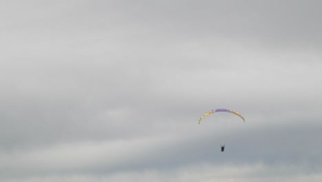 toma de teleobjetivo de un solo parapente volando en la distancia durante el día nublado