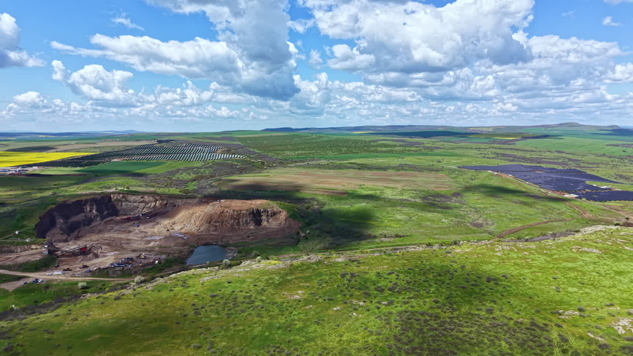 Stor åben grube i et grønt landskab med skyer ovenover, der viser lys og skygge i naturlige omgivelser.