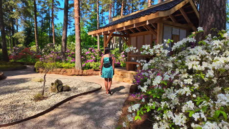 visitors explore a serene japanese garden surrounded by colorful flowers and tall trees