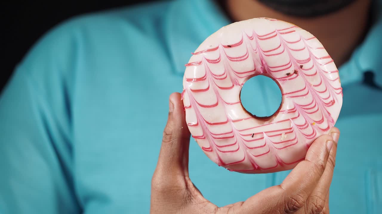 Persona che Tiene una Ciambella Glassata Rosa e Bianca