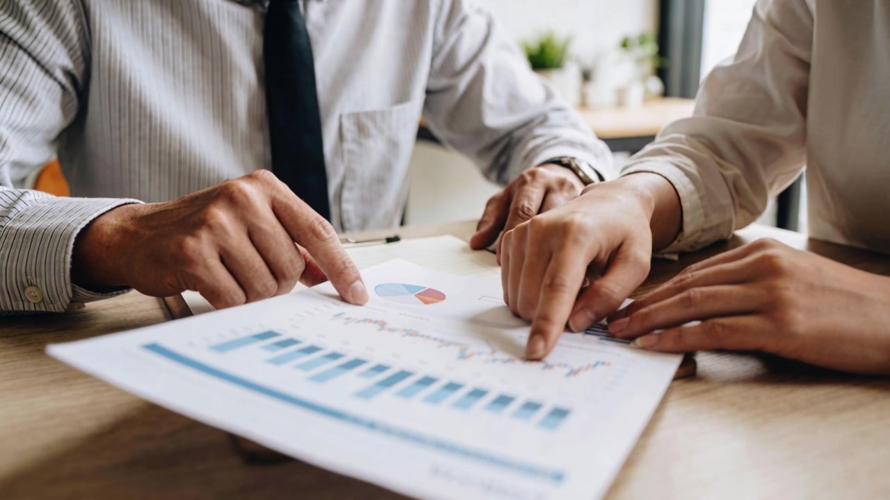 Report landing sparking professionals in office wear at desk pointing at line chart comparing trend