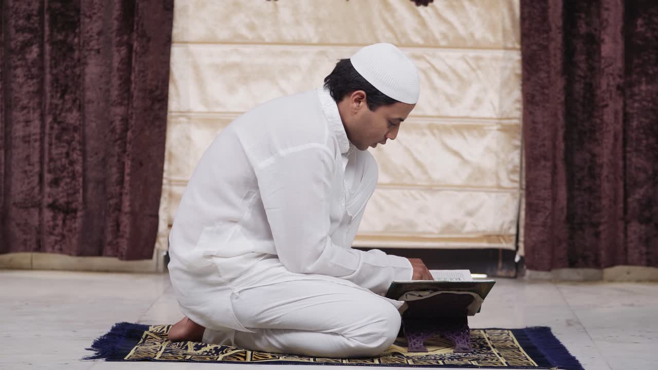 인도 무슬림 남자가 집에서 꾸란 책을 읽고 있습니다.