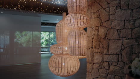 cluster of wicker pendant lights hanging beside a rustic stone wall in a modern indoor setting