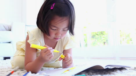 girl using a marker to colour in a colouring book