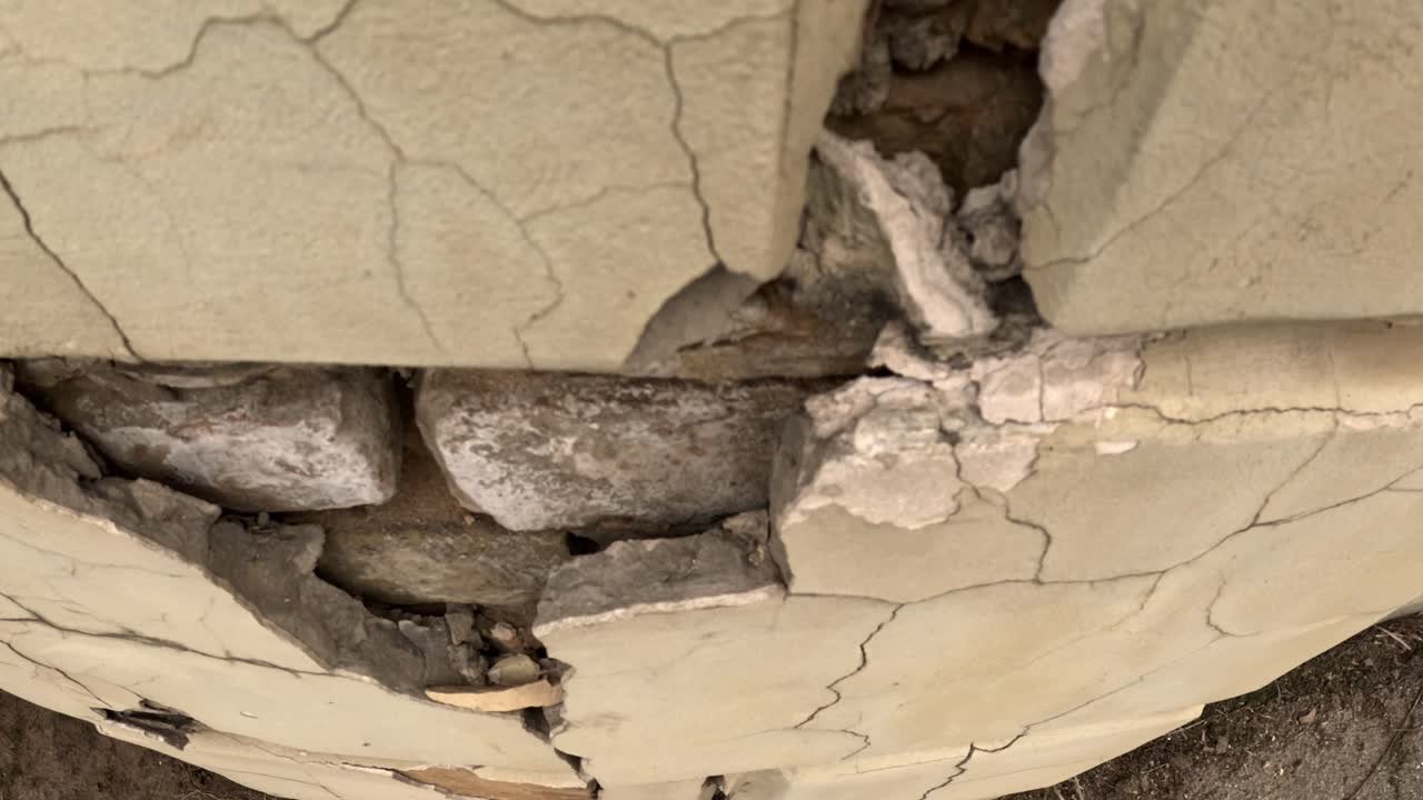 A close-up shot reveals the textured, broken surface of a wall, showcasing cracks and decay in intricate detail.