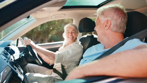 senior couple enjoying day trip out driving and sightseeing in car together